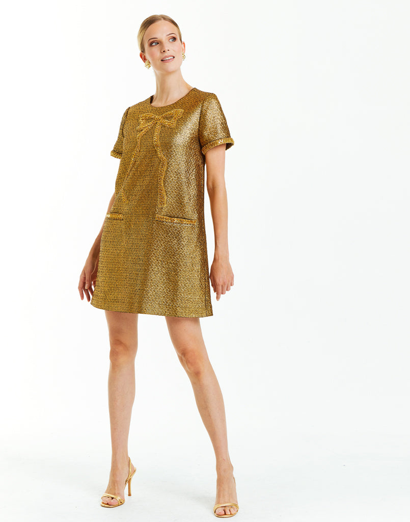 Metallic gold tweed cocktail mini dress with short sleeves, front pockets, and a fancy bow embellishment. 