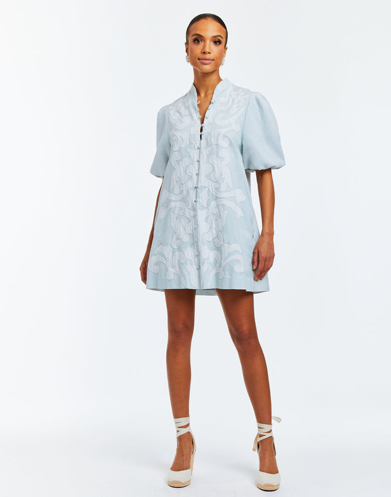 A-line mini dress with a mandarin collar, puff sleeves, pockets and embroidered flourishes. 