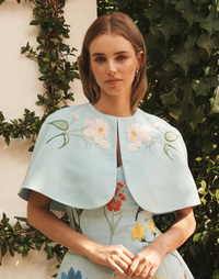 Promenade Embroidered Capelet in Blue Waltz moire with hand-sewn floral embroidery, crew neckline, and hook-and-eye closure.