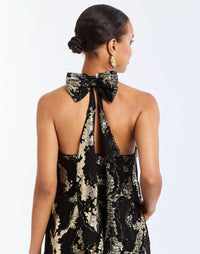 Adelina Gown in Black/Gold detail – metallic jacquard evening gown with halter bow neckline, faux ruffle back, A-line silhouette, and side seam pockets by Mestiza New York.