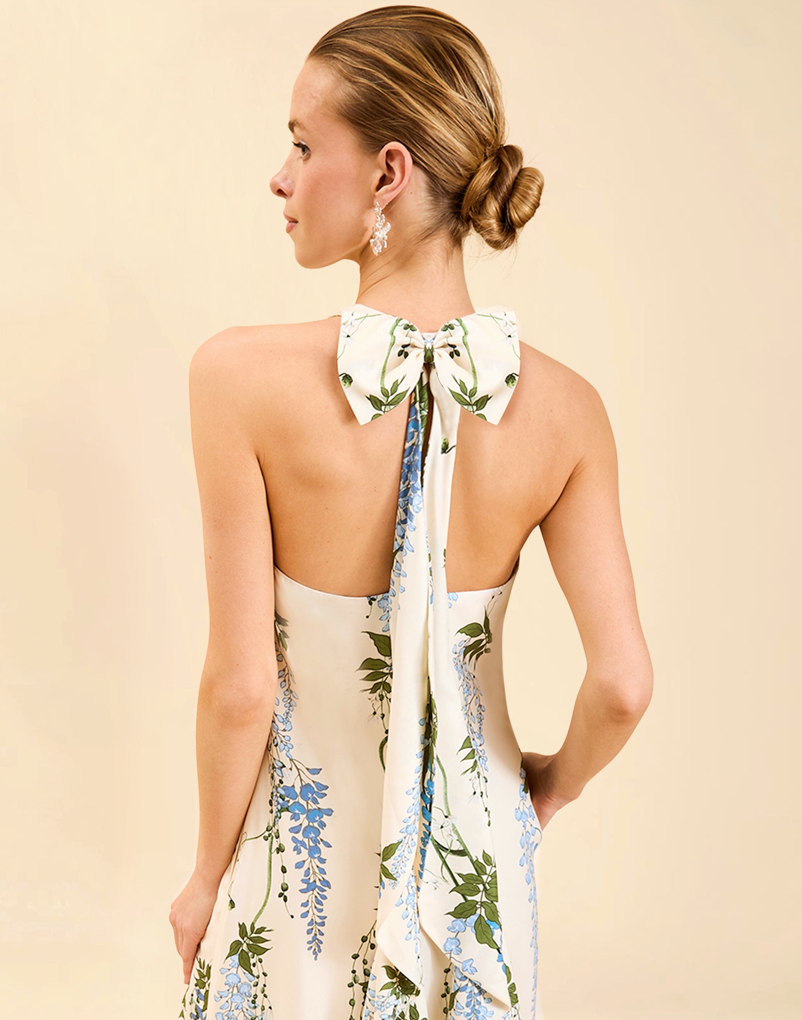 Adelina Gown in Wisteria Toile stretch crepe with halter neckline, cascading bow back detail, A-line silhouette, and hidden side pockets.