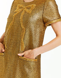 Metallic gold tweed cocktail mini dress with short sleeves, front pockets, and a fancy bow embellishment. 