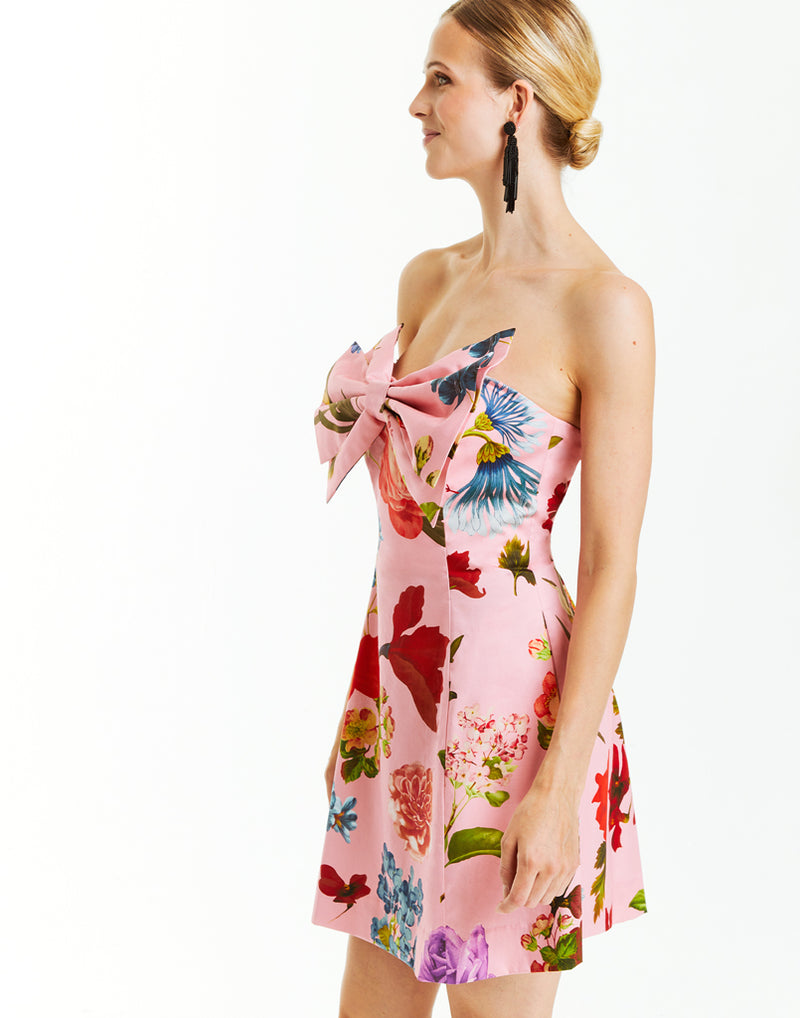 pink strapless mini dress with bold pink garden floral print and oversized front bow detail.