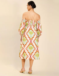 Woman wearing the Mestiza Benny Midi Dress in Mediterranean Sage print, featuring an off-the-shoulder neckline, empire waist, balloon sleeves, A-line skirt, and breathable linen fabrication.