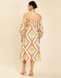 Woman wearing the Mestiza Benny Midi Dress in Mediterranean Sage print, featuring an off-the-shoulder neckline, empire waist, balloon sleeves, A-line skirt, and breathable linen fabrication.