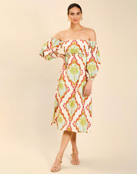 Woman wearing the Mestiza Benny Midi Dress in Mediterranean Sage print, featuring an off-the-shoulder neckline, empire waist, balloon sleeves, A-line skirt, and breathable linen fabrication.