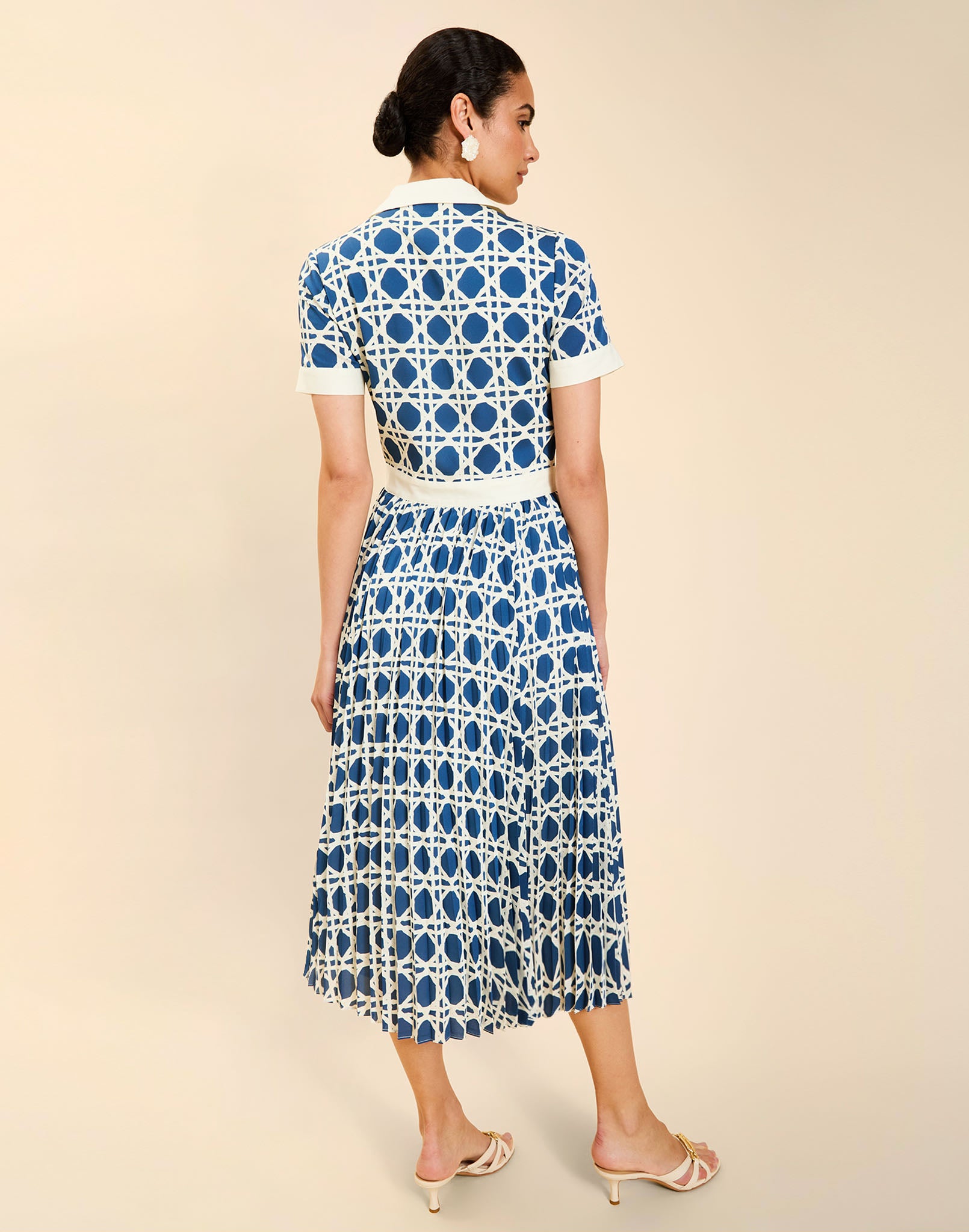 Woman wearing the Mestiza Billie Collared Shirt Dress in Solihiya Navy print, featuring a collared neckline, pleated midi skirt, contrast ivory button placket and cuffs, and lightweight twill fabrication.