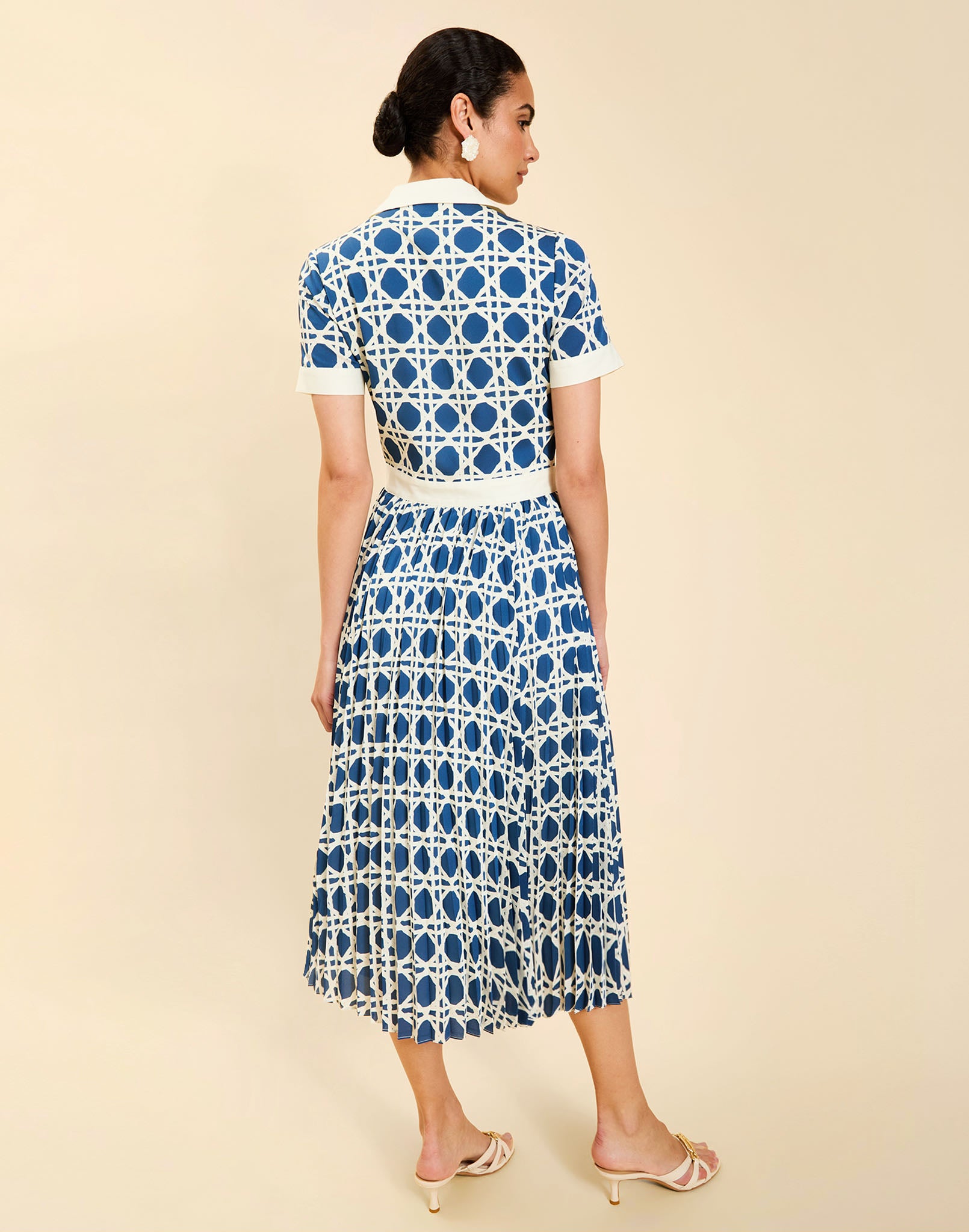 Woman wearing the Mestiza Billie Collared Shirt Dress in Solihiya Navy print, featuring a collared neckline, pleated midi skirt, contrast ivory button placket and cuffs, and lightweight twill fabrication.