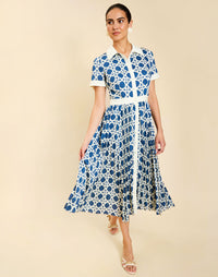 Woman wearing the Mestiza Billie Collared Shirt Dress in Solihiya Navy print, featuring a collared neckline, pleated midi skirt, contrast ivory button placket and cuffs, and lightweight twill fabrication.