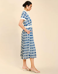 Woman wearing the Mestiza Billie Collared Shirt Dress in Solihiya Navy print, featuring a collared neckline, pleated midi skirt, contrast ivory button placket and cuffs, and lightweight twill fabrication.