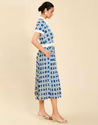Woman wearing the Mestiza Billie Collared Shirt Dress in Solihiya Navy print, featuring a collared neckline, pleated midi skirt, contrast ivory button placket and cuffs, and lightweight twill fabrication.