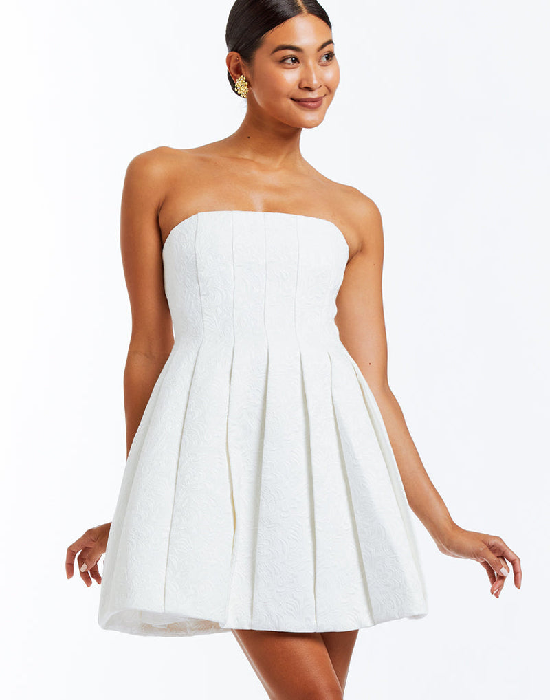 Strapless ivory jacquard mini cocktail dress with a bell-shaped silhouette and box pleats for additional textural detail.