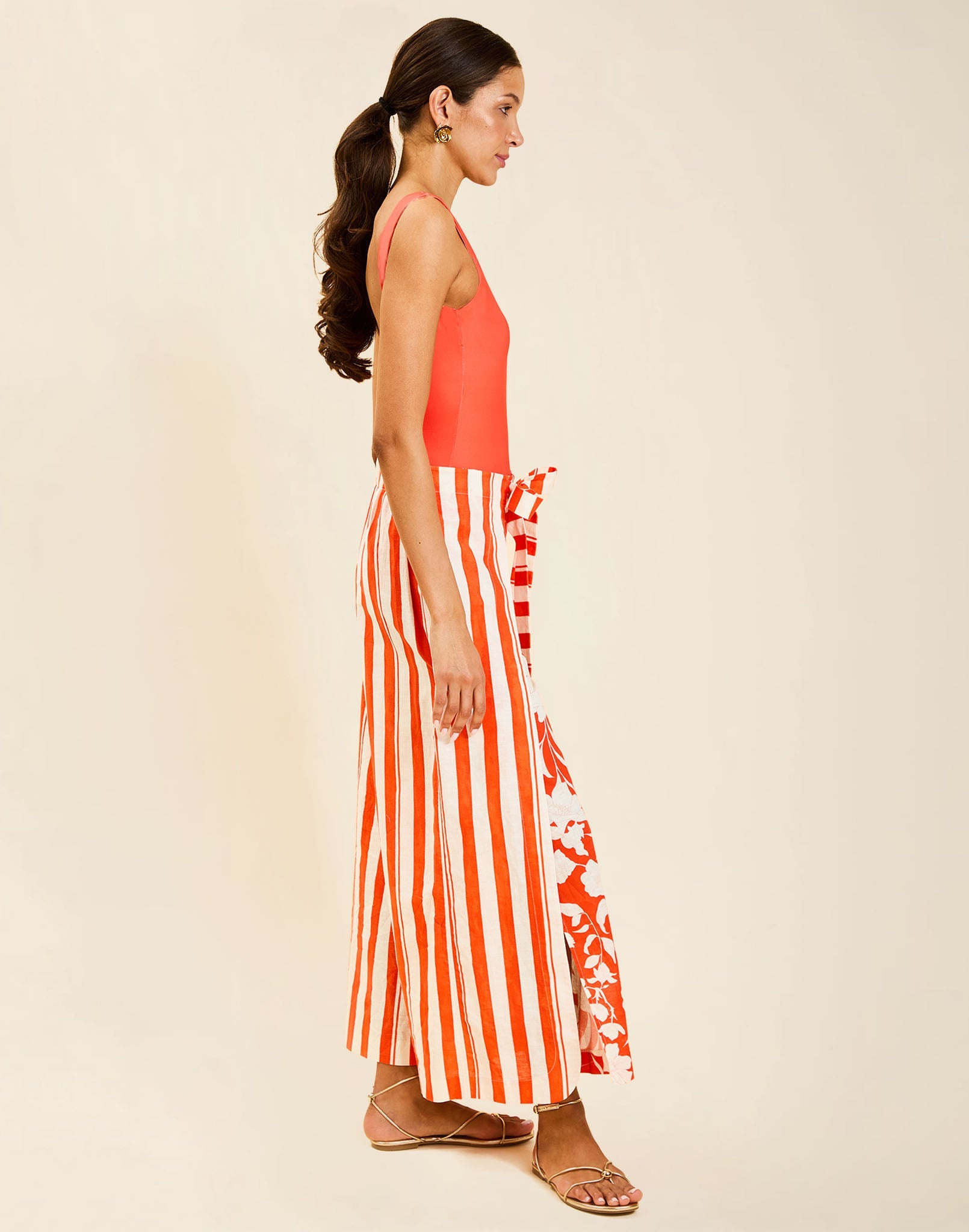 Model wearing Chloe Wrap Beach Pant in Mandarin Stripe cotton-linen blend with wraparound panel and self-tie bow.