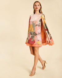 Collins Cape Mini Dress in Painted Blooms sequin with a boat neckline, draped cape, and flutter hem.
