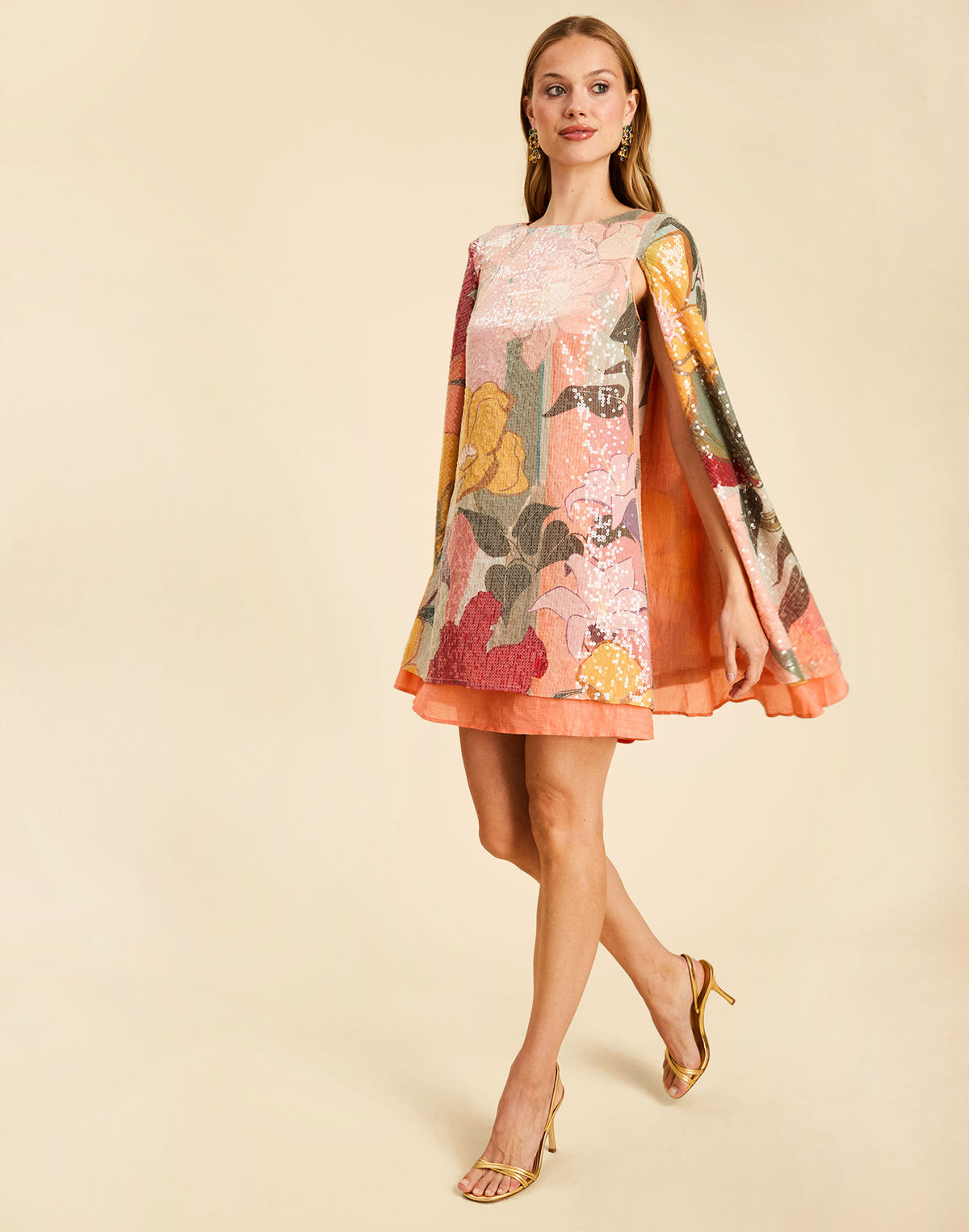 Collins Cape Mini Dress in Painted Blooms sequin with a boat neckline, draped cape, and flutter hem.
