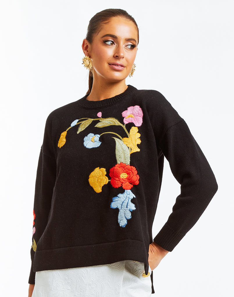 Black crew neck with relaxed fit and includes bold, colorful embroidered flowers.