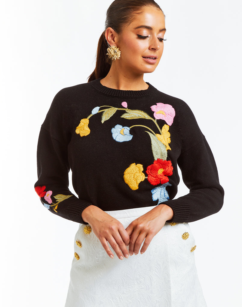 Black crew neck with relaxed fit and includes bold, colorful embroidered flowers.