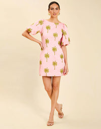 Woman wearing the Mestiza Donovan Mini Dress in English Rose, featuring a boat neckline, embroidered cotton poplin fabrication, fitted waist, balloon sleeves, subtle A-line skirt, and side seam pockets.