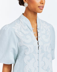 A-line mini dress with a mandarin collar, puff sleeves, pockets and embroidered flourishes. 