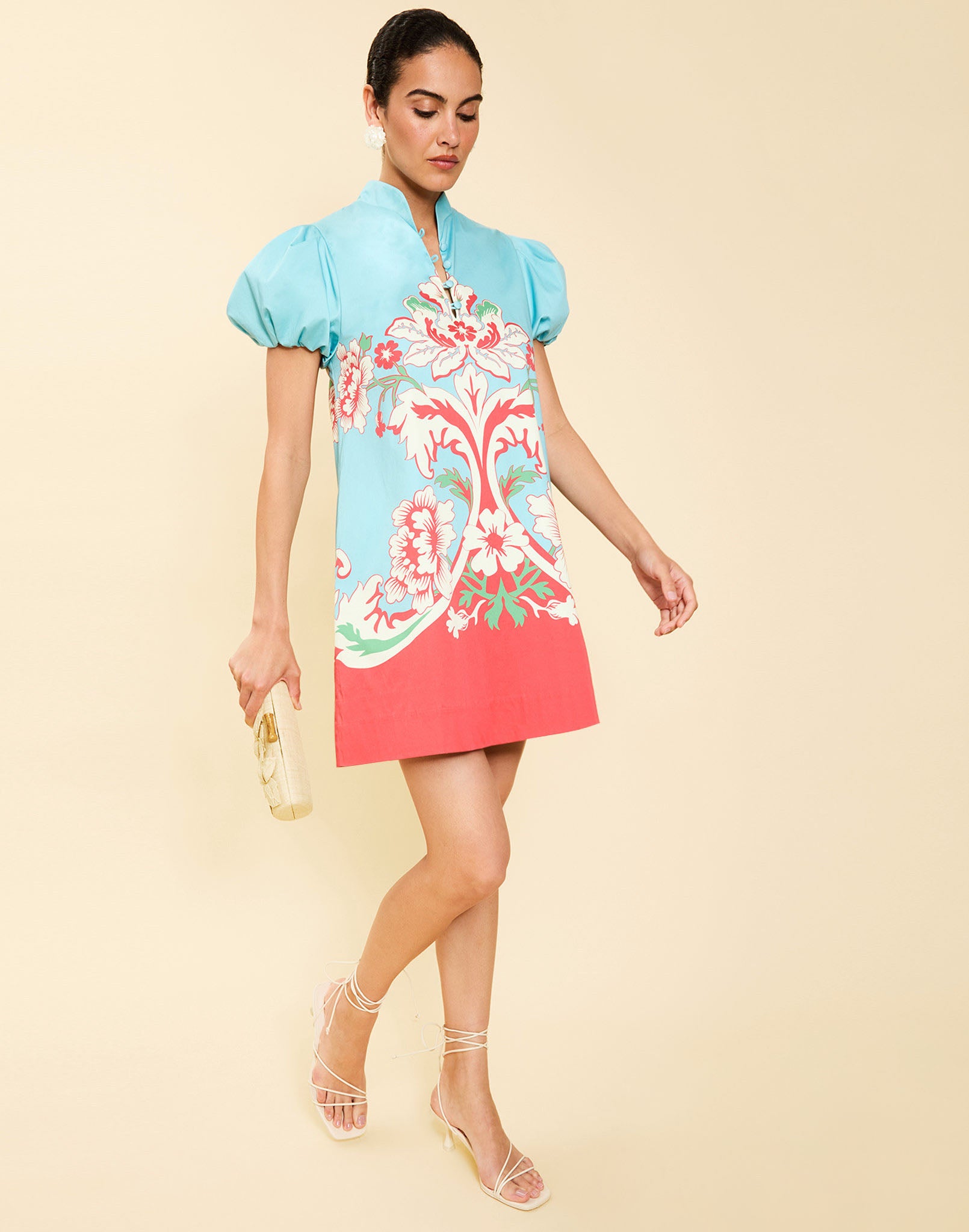 Woman wearing the Mestiza Elliana Mini Dress in La Botanica Blue print, featuring an A-line silhouette, mandarin collar, V-neckline, pleated puff sleeves, and cotton poplin fabrication.