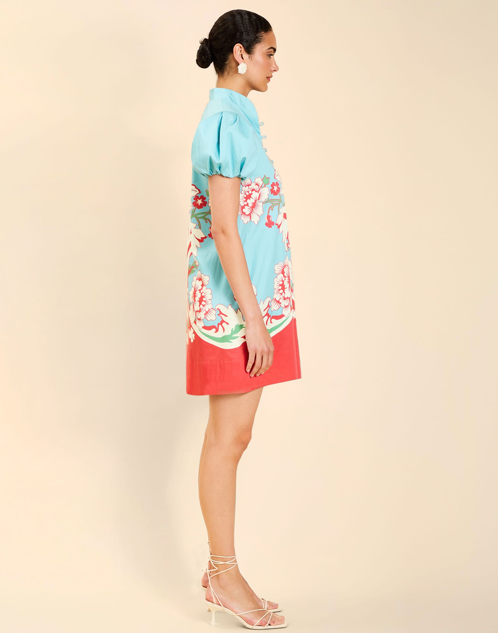 Woman wearing the Mestiza Elliana Mini Dress in La Botanica Blue print, featuring an A-line silhouette, mandarin collar, V-neckline, pleated puff sleeves, and cotton poplin fabrication.