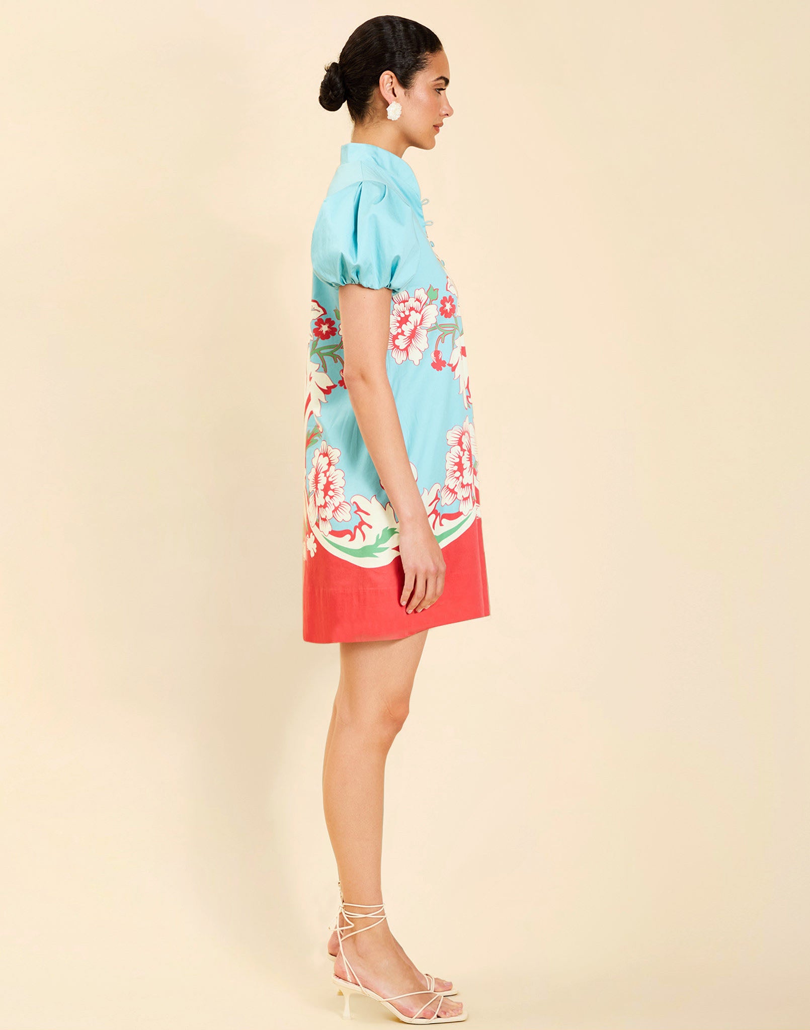 Woman wearing the Mestiza Elliana Mini Dress in La Botanica Blue print, featuring an A-line silhouette, mandarin collar, V-neckline, pleated puff sleeves, and cotton poplin fabrication.
