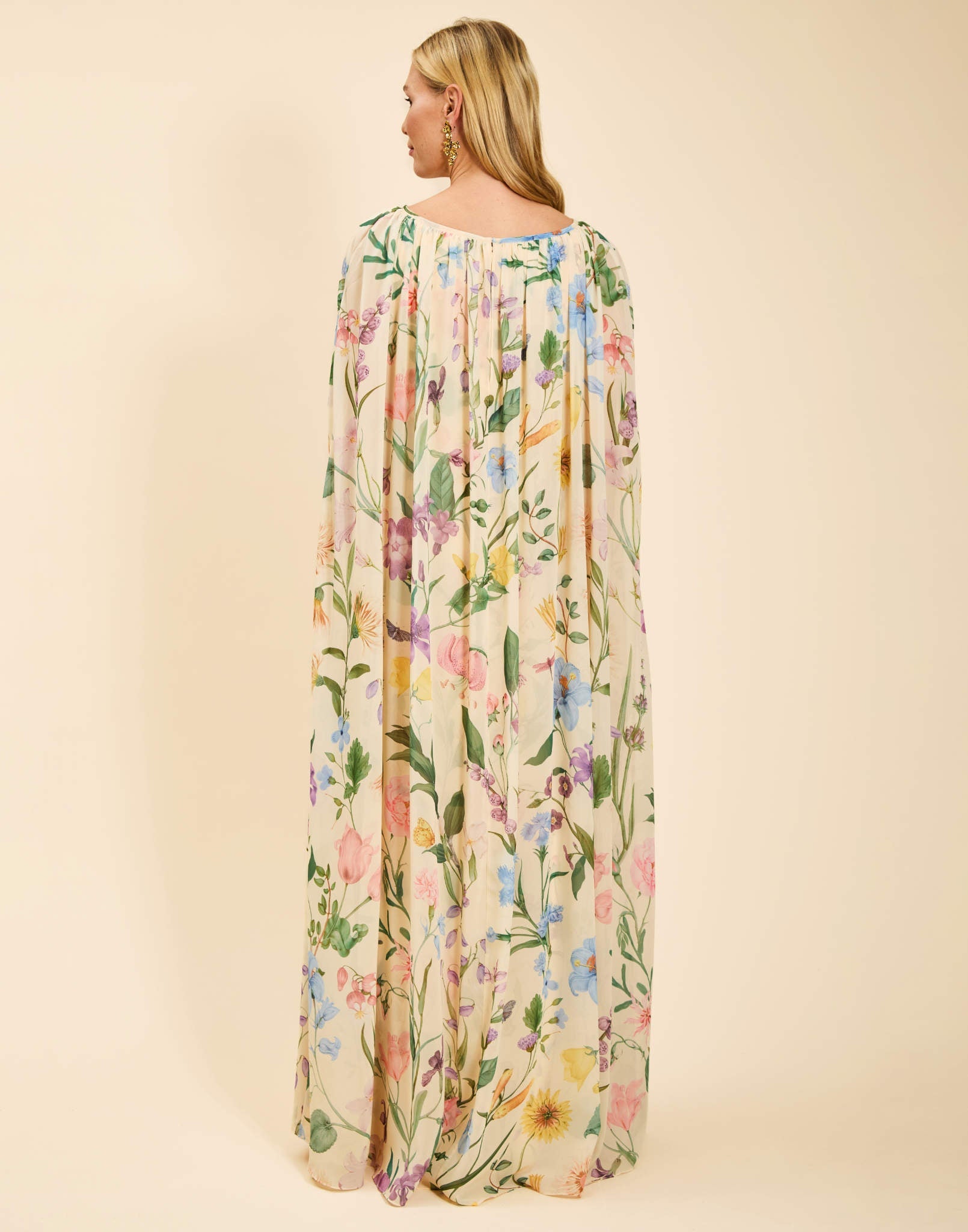Estrella Cape Gown in Blooming Vine chiffon with attached cape, boat neckline, flowing column silhouette, and side seam pockets.