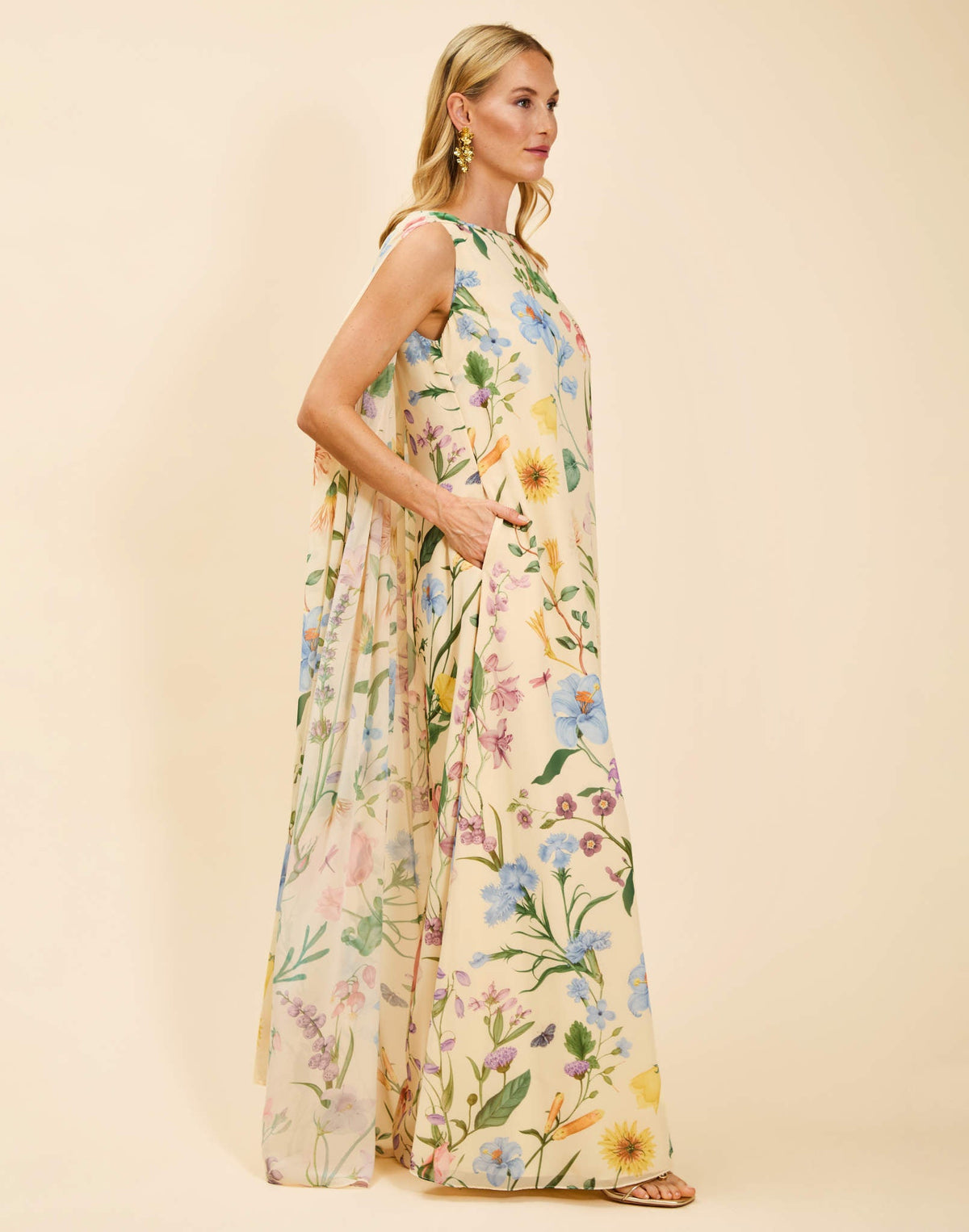 Estrella Cape Gown in Blooming Vine chiffon with attached cape, boat neckline, flowing column silhouette, and side seam pockets.