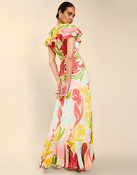 Woman wearing the Mestiza Fernanda Gown in Autumn Daydreaming print, featuring a V-neckline, cascading ruffle details, cap-style ruffle sleeves, fitted bodice, and flowing chiffon skirt.