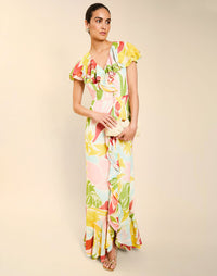 Woman wearing the Mestiza Fernanda Gown in Autumn Daydreaming print, featuring a V-neckline, cascading ruffle details, cap-style ruffle sleeves, fitted bodice, and flowing chiffon skirt.