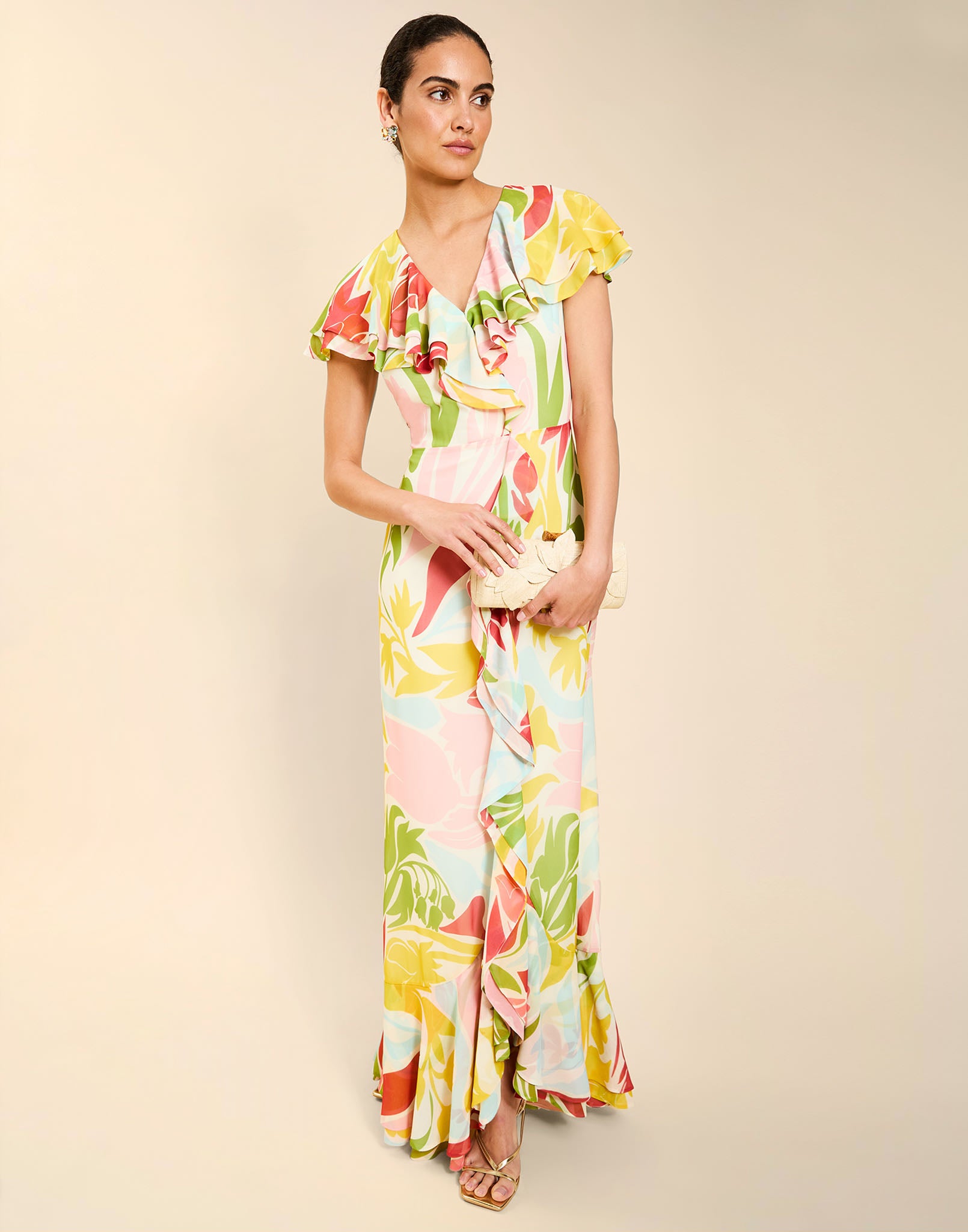 Woman wearing the Mestiza Fernanda Gown in Autumn Daydreaming print, featuring a V-neckline, cascading ruffle details, cap-style ruffle sleeves, fitted bodice, and flowing chiffon skirt.