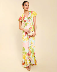 Woman wearing the Mestiza Fernanda Gown in Autumn Daydreaming print, featuring a V-neckline, cascading ruffle details, cap-style ruffle sleeves, fitted bodice, and flowing chiffon skirt.