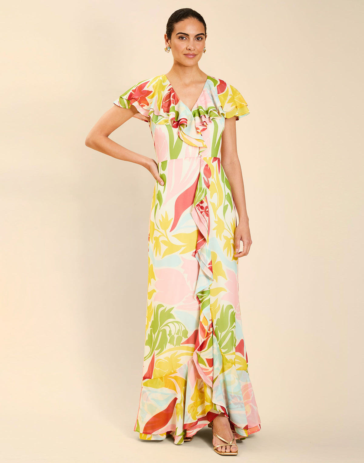 Woman wearing the Mestiza Fernanda Gown in Autumn Daydreaming print, featuring a V-neckline, cascading ruffle details, cap-style ruffle sleeves, fitted bodice, and flowing chiffon skirt.