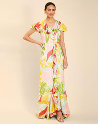 Woman wearing the Mestiza Fernanda Gown in Autumn Daydreaming print, featuring a V-neckline, cascading ruffle details, cap-style ruffle sleeves, fitted bodice, and flowing chiffon skirt.