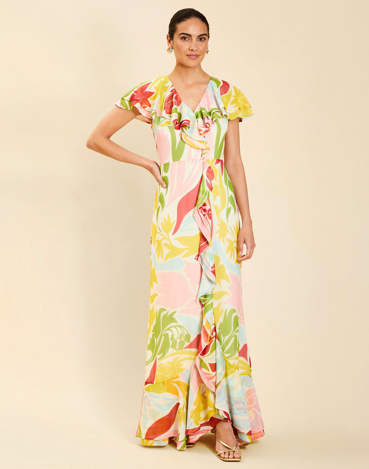Woman wearing the Mestiza Fernanda Gown in Autumn Daydreaming print, featuring a V-neckline, cascading ruffle details, cap-style ruffle sleeves, fitted bodice, and flowing chiffon skirt.