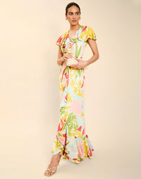 Woman wearing the Mestiza Fernanda Gown in Autumn Daydreaming print, featuring a V-neckline, cascading ruffle details, cap-style ruffle sleeves, fitted bodice, and flowing chiffon skirt.