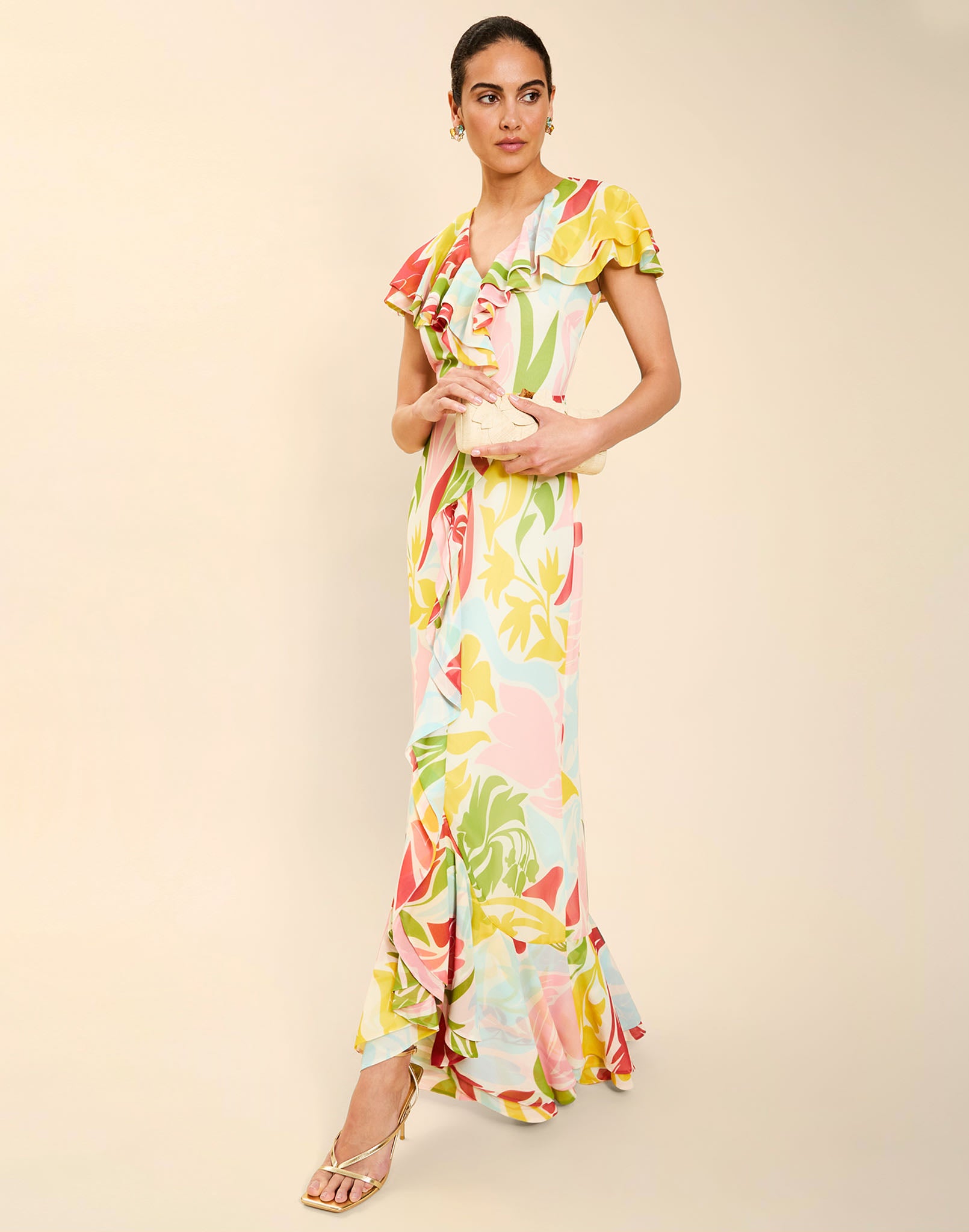 Woman wearing the Mestiza Fernanda Gown in Autumn Daydreaming print, featuring a V-neckline, cascading ruffle details, cap-style ruffle sleeves, fitted bodice, and flowing chiffon skirt.