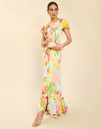 Woman wearing the Mestiza Fernanda Gown in Autumn Daydreaming print, featuring a V-neckline, cascading ruffle details, cap-style ruffle sleeves, fitted bodice, and flowing chiffon skirt.