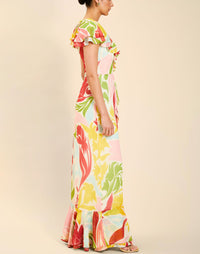 Woman wearing the Mestiza Fernanda Gown in Autumn Daydreaming print, featuring a V-neckline, cascading ruffle details, cap-style ruffle sleeves, fitted bodice, and flowing chiffon skirt.