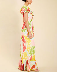 Woman wearing the Mestiza Fernanda Gown in Autumn Daydreaming print, featuring a V-neckline, cascading ruffle details, cap-style ruffle sleeves, fitted bodice, and flowing chiffon skirt.