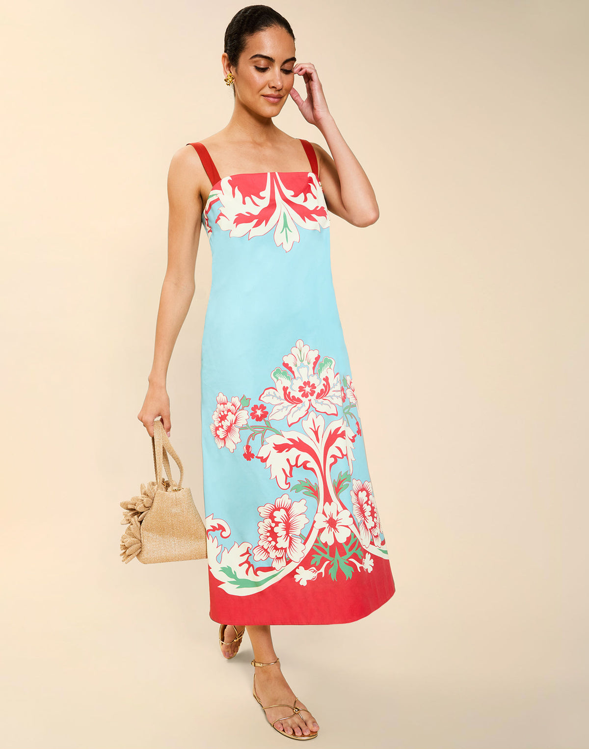 Woman wearing the Mestiza Galena Tea Length Dress in La Botanica Blue print, featuring a column silhouette, straight-across neckline, adjustable straps, side seam pockets, and cotton poplin fabrication.