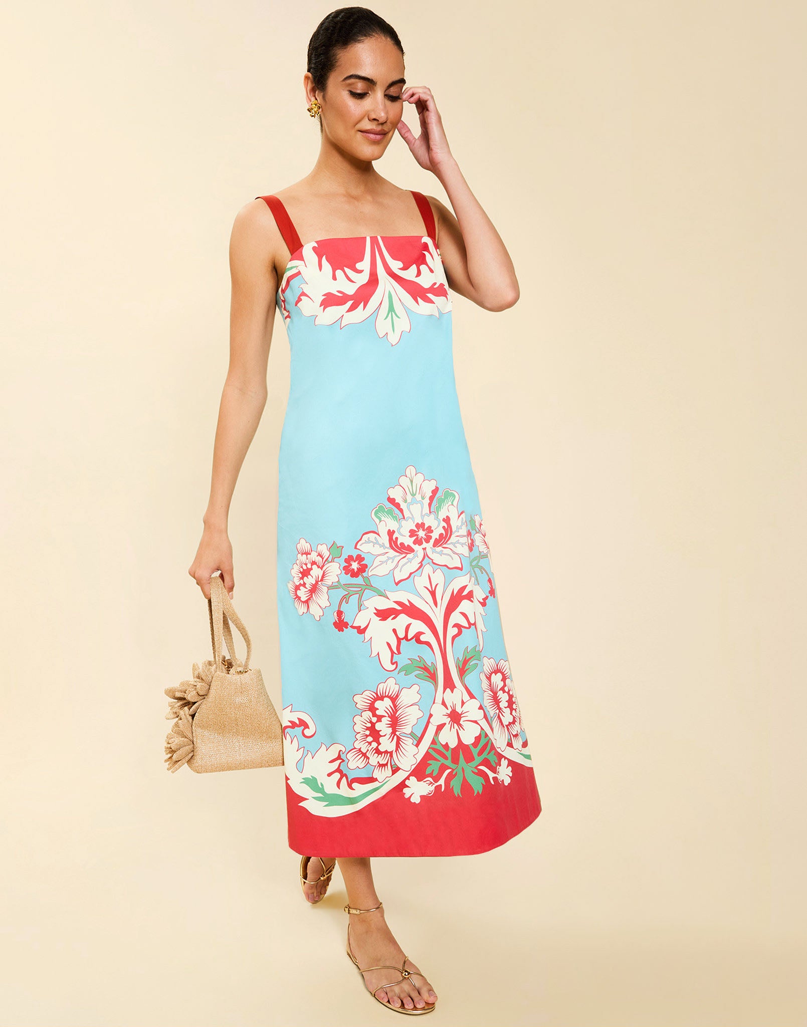 Woman wearing the Mestiza Galena Tea Length Dress in La Botanica Blue print, featuring a column silhouette, straight-across neckline, adjustable straps, side seam pockets, and cotton poplin fabrication.