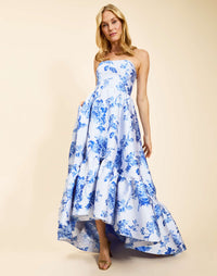 Strapless gown in Porcelain Blue Jacquard featuring a fitted bodice, cascading asymmetrical skirt, removable straps, and functional pockets.