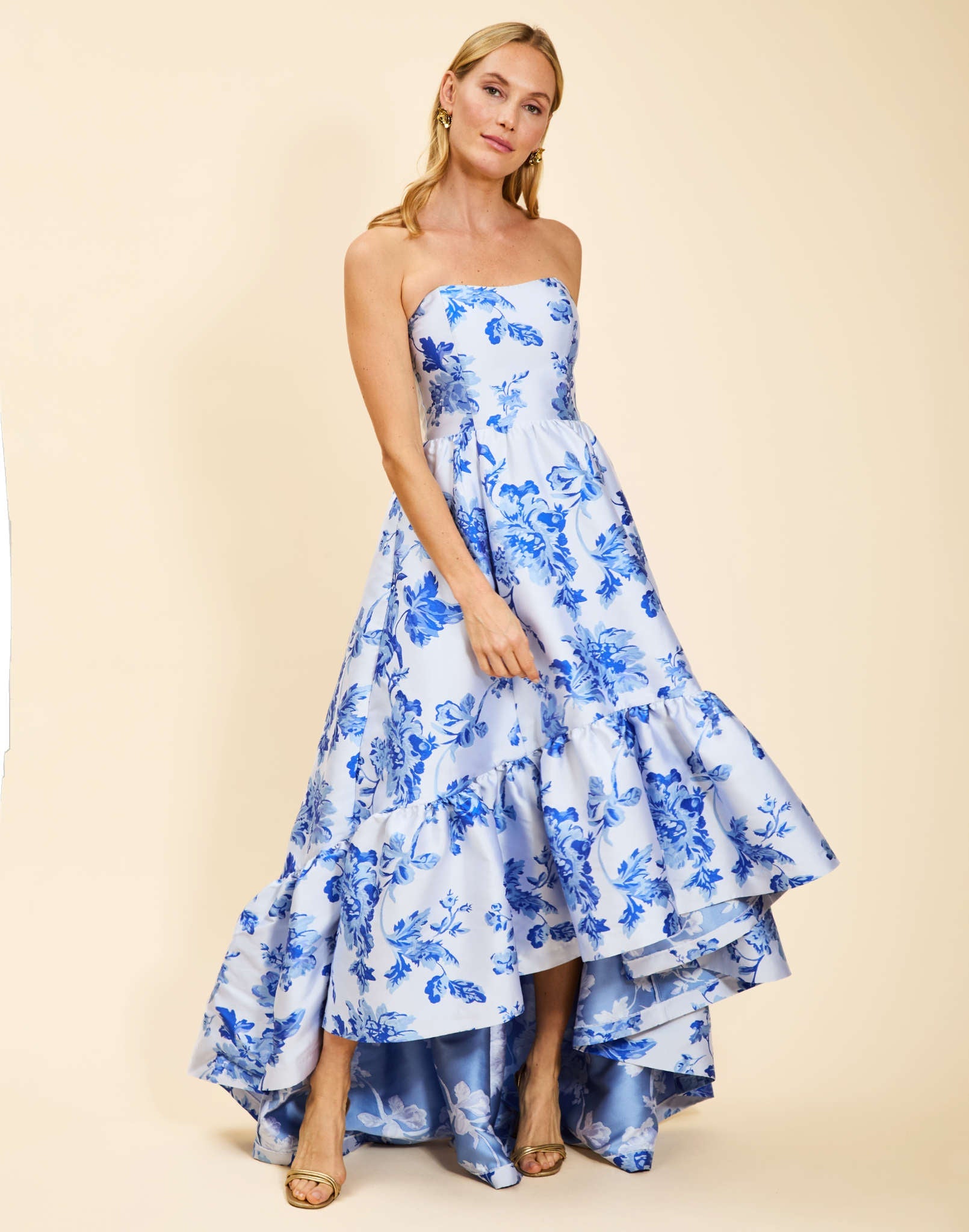 Strapless gown in Porcelain Blue Jacquard featuring a fitted bodice, cascading asymmetrical skirt, removable straps, and functional pockets.