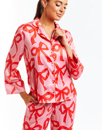 Pink pajama set with red bow print, red piping and side pockets. 