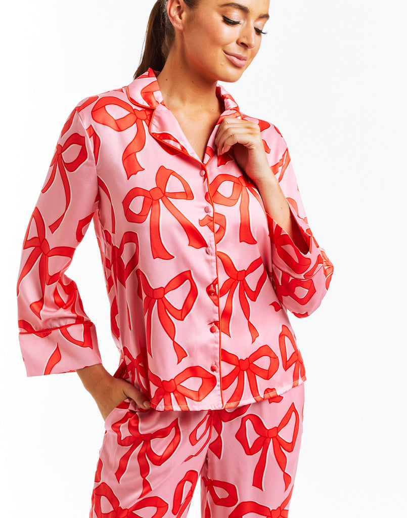 Pink pajama set with red bow print, red piping and side pockets. 