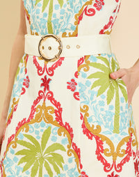 Woman wearing the Mestiza Havana Mini Dress in Mediterranean Sage print, featuring a bib-neckline, bell skirt, removable belt, thin straps, and cotton poplin fabrication.