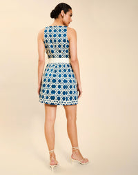 Woman wearing the Mestiza Havana Mini Dress in Solihiya Navy print, featuring a bib-neckline, bell skirt, removable belt, princess seaming, side seam pockets, and cotton poplin fabrication.