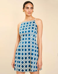 Woman wearing the Mestiza Havana Mini Dress in Solihiya Navy print, featuring a bib-neckline, bell skirt, removable belt, princess seaming, side seam pockets, and cotton poplin fabrication.