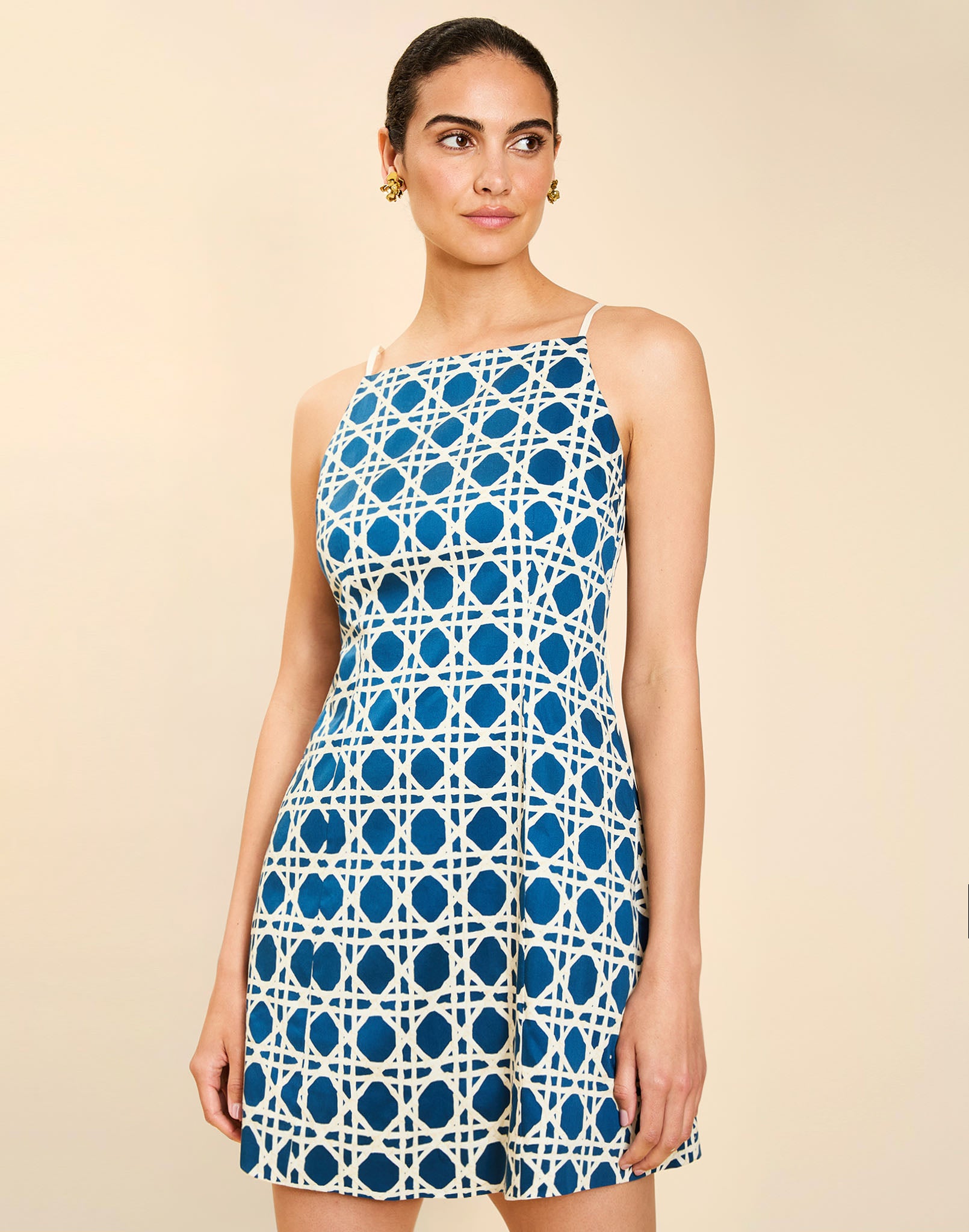 Woman wearing the Mestiza Havana Mini Dress in Solihiya Navy print, featuring a bib-neckline, bell skirt, removable belt, princess seaming, side seam pockets, and cotton poplin fabrication.